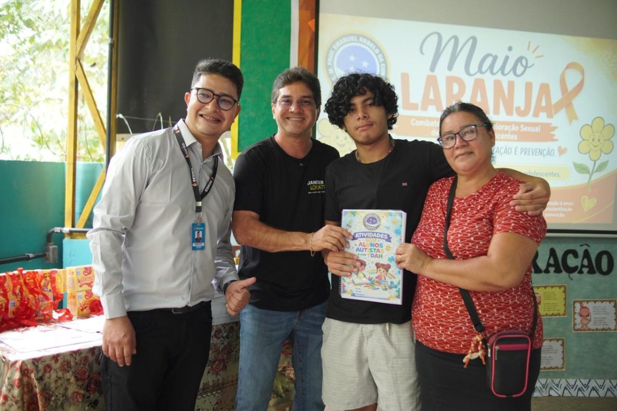 Quatro pessoas posam em uma escola durante entrega de apostilas sobre autismo e TDAH promovida pelo vereador Jander Lobato em Manaus.